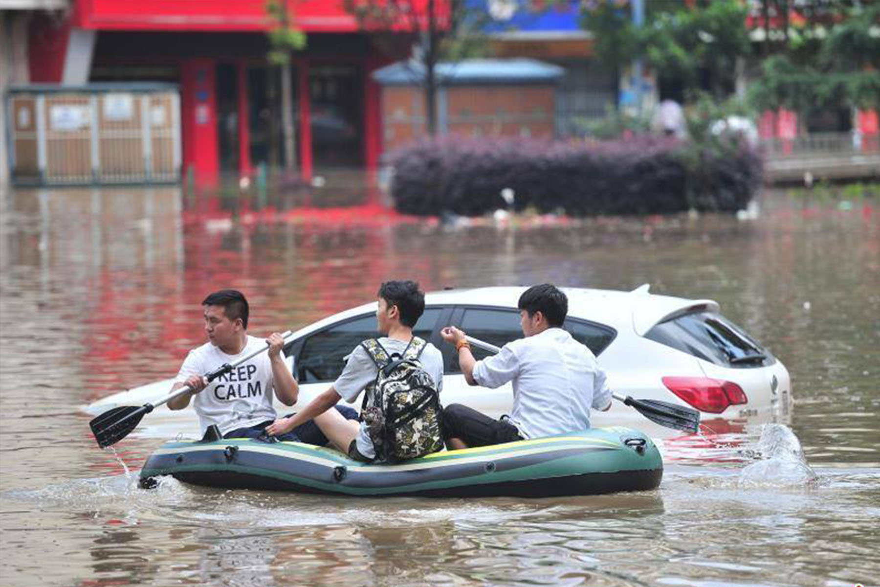 three men on a rubber boat on a flooded street in kunming yunnan china